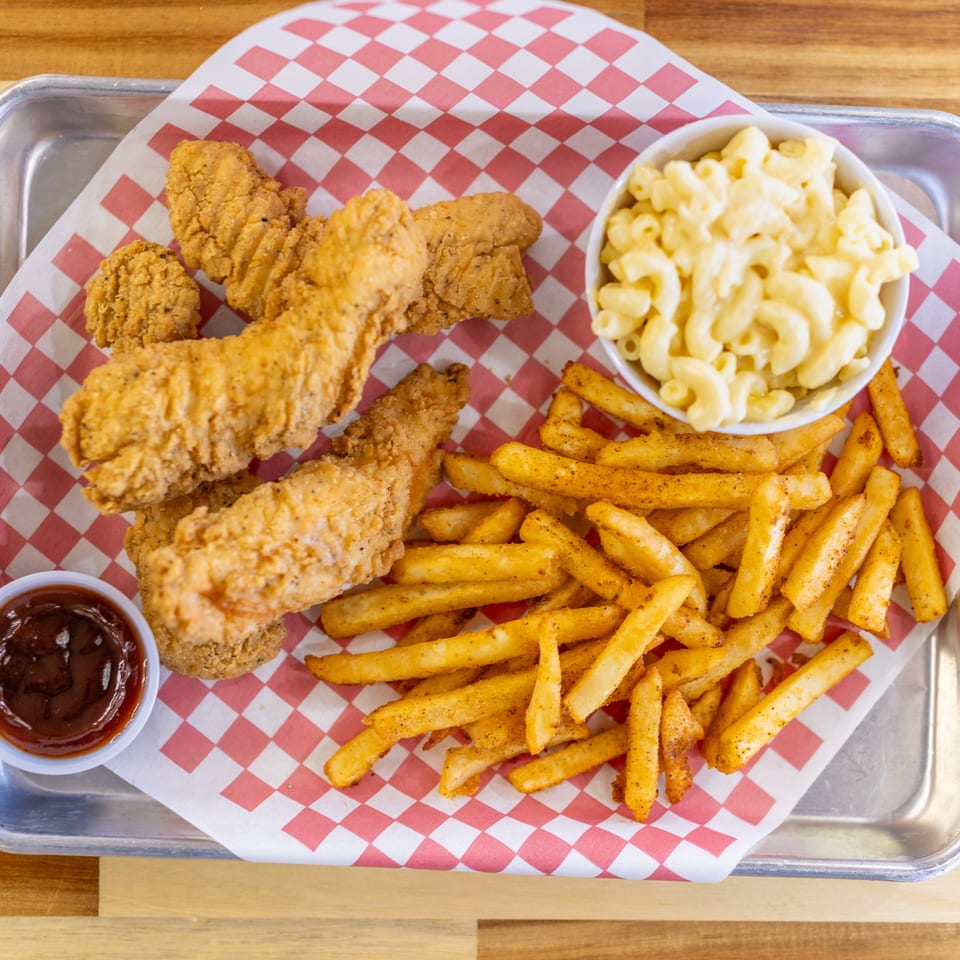 Dave's BBQ & Smokehouse chicken tenders, fries, mac and cheese, and BBQ sauce on a tray.